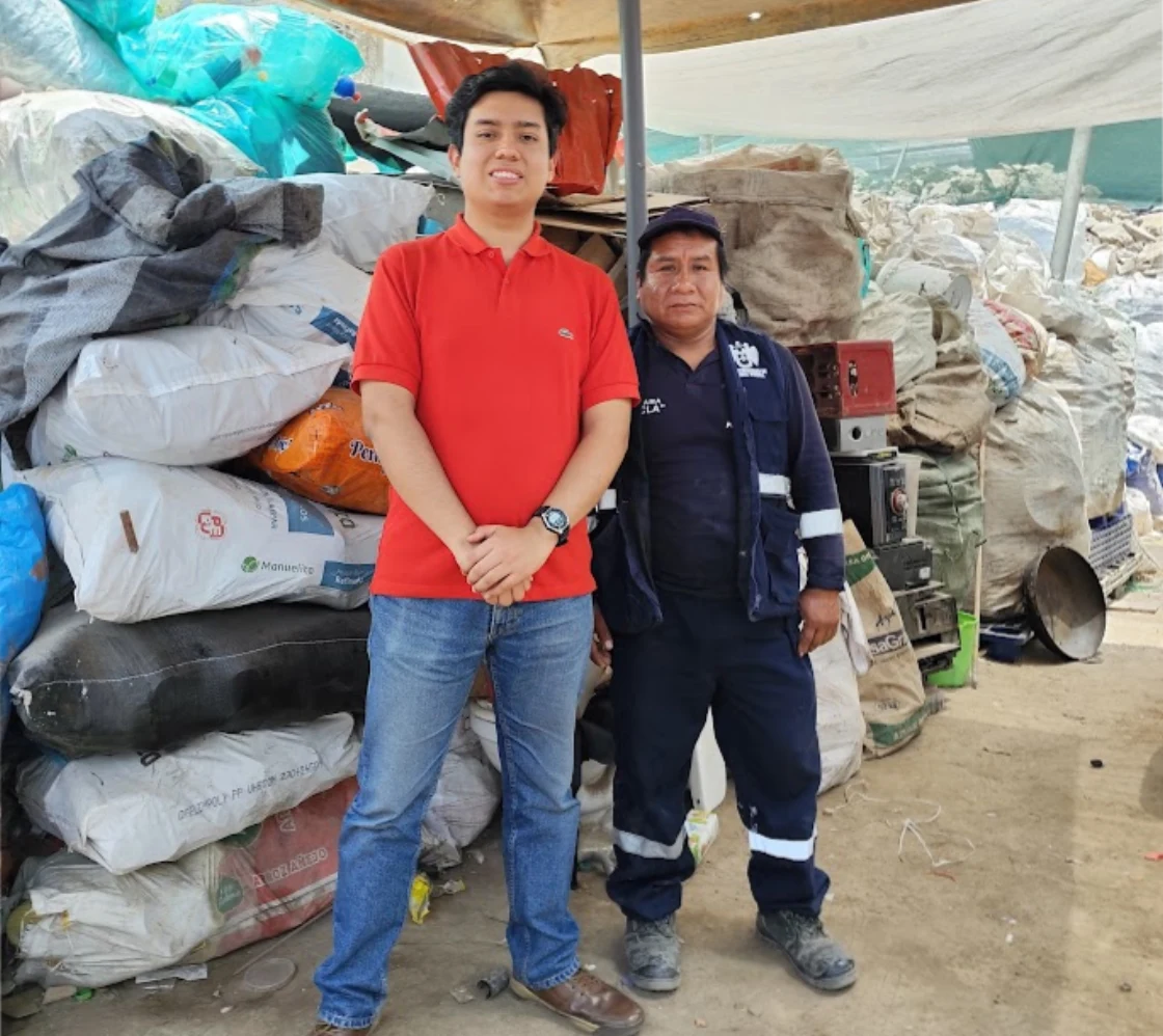 Integrante de Reganvi junto a un reciclador en su centro de acopio de Puente Piedra, rodeados de sacos de material